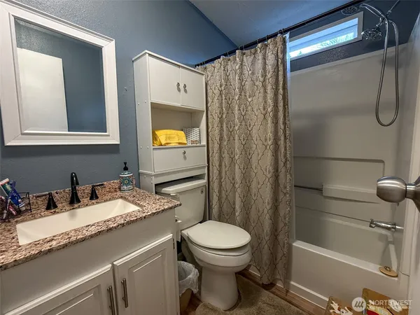 a bathroom with a granite countertop sink toilet and shower
