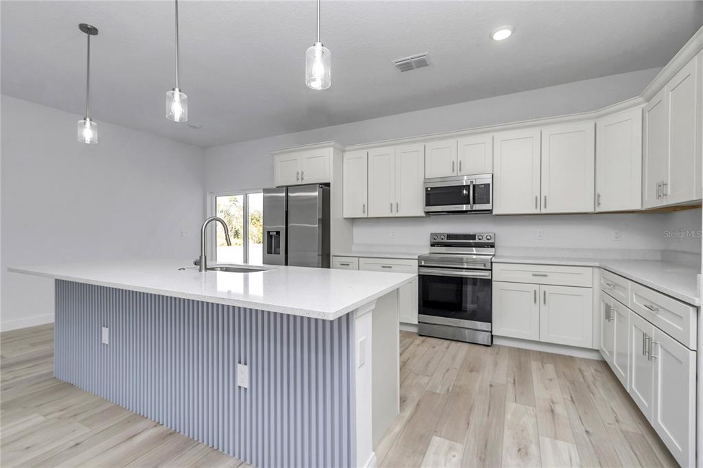 15227 Southwest 28th Avenue Road Ocala, FL 34473 - Photo 16 of 38 a kitchen with kitchen island granite countertop white cabinets and stainless steel appliances