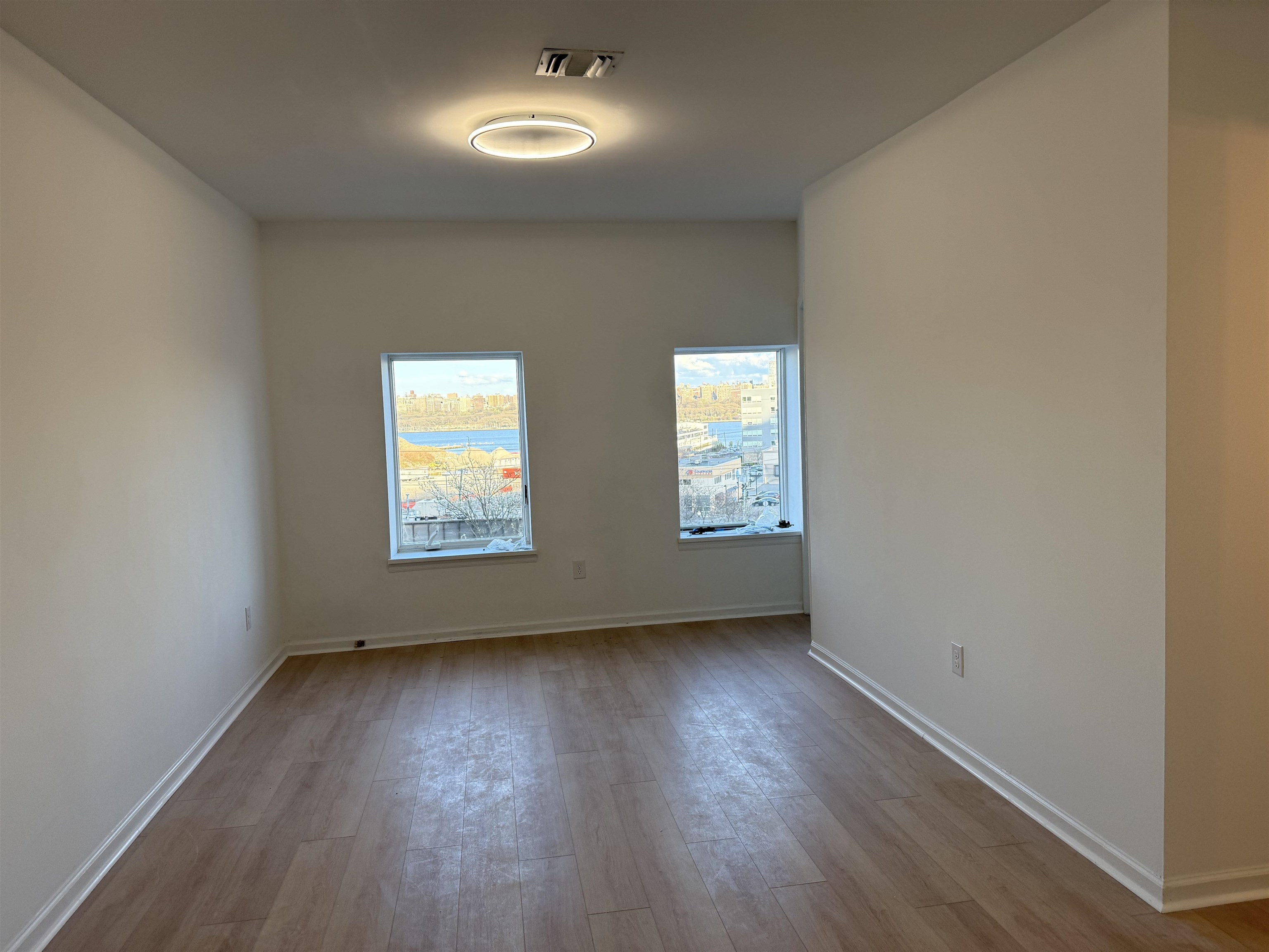 9007 Riverside Place, Unit 3 North Bergen, NJ 07047 - Photo 13 of 18 an empty room with wooden floor and windows