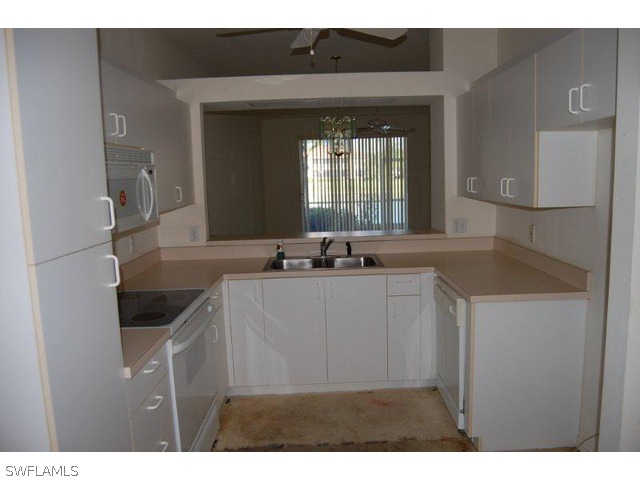 300 Robin Hood Circle, Unit 102 Naples, FL 34104 - Photo 2 of 8 a kitchen with a sink and a refrigerator