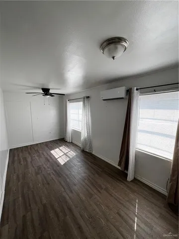a view of empty room with window and wooden floor
