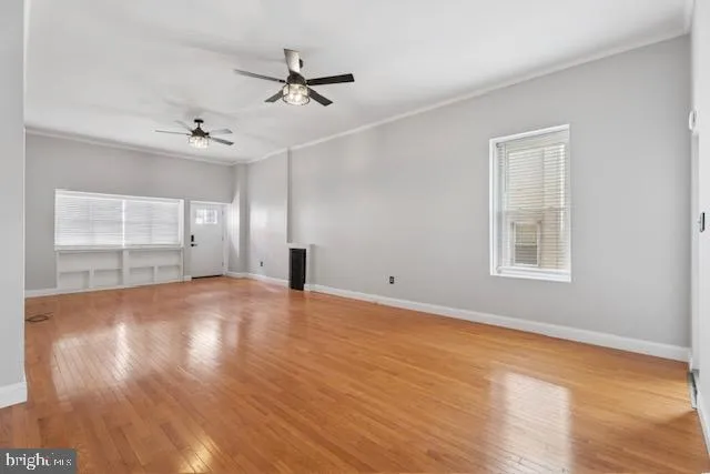 a view of empty room with wooden floor and fan
