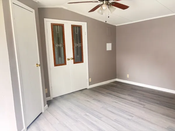 an empty room with wooden floor fan and windows