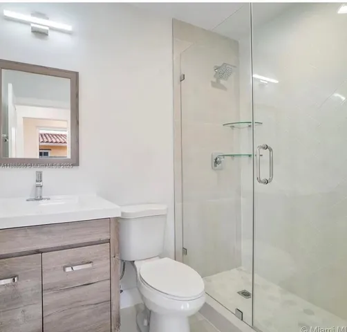 a bathroom with a toilet sink vanity and shower