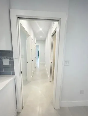 a view of a hallway with white walls and entryway