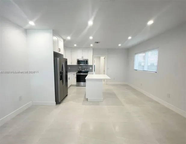 a view of a kitchen with refrigerator and windows