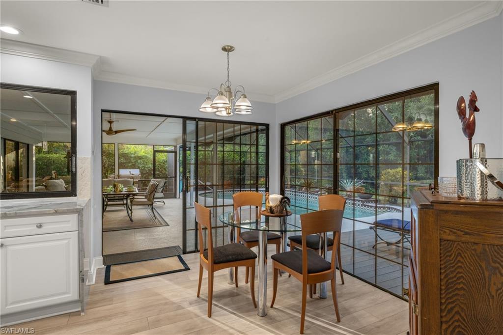 2259 Queens Way Naples, FL 34112 - Photo 14 of 29 a dining room with furniture large windows and a chandelier