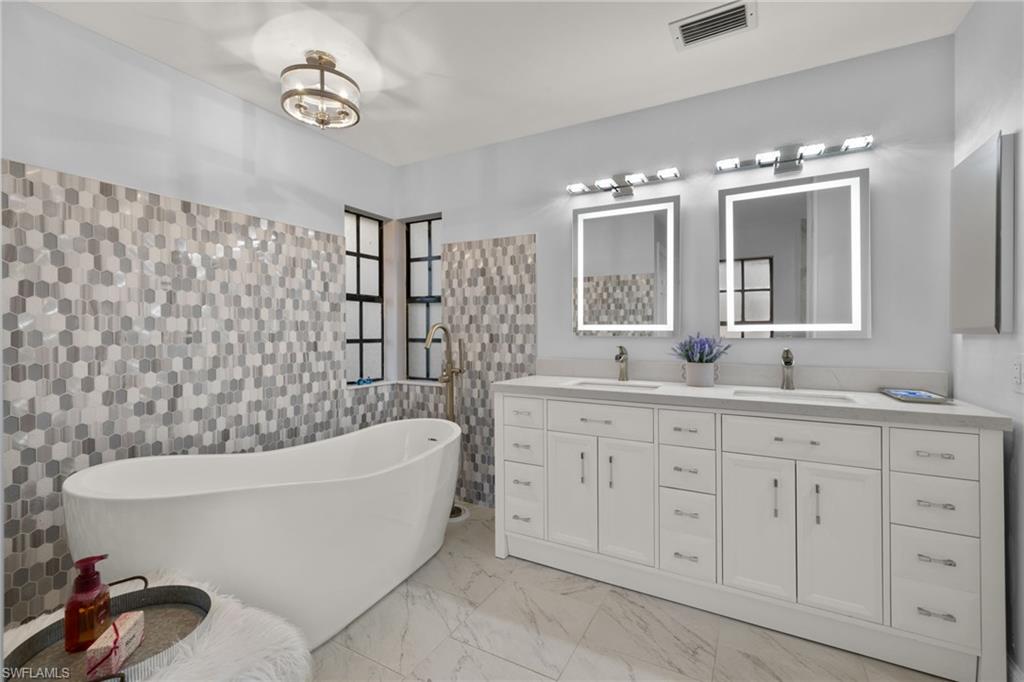 2259 Queens Way Naples, FL 34112 - Photo 20 of 29 a bathroom with a bathtub sink and mirror