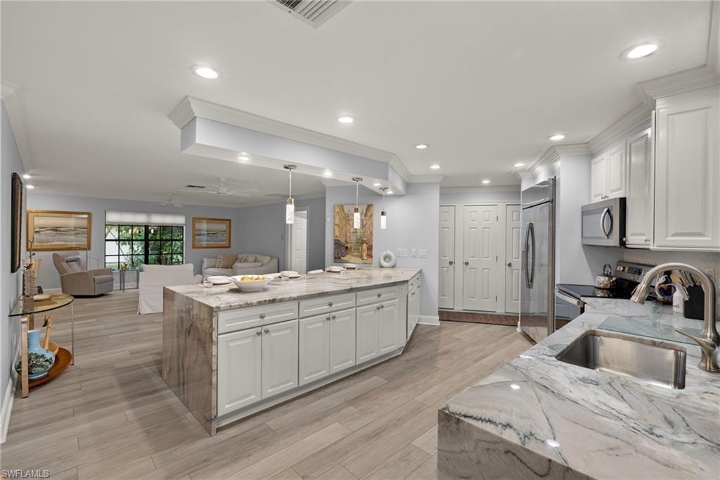 2259 Queens Way Naples, FL 34112 - Photo 10 of 29 a large white kitchen with a sink and dishwasher a stove with wooden floor