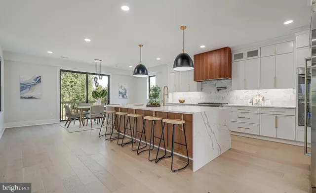 a kitchen with granite countertop a stove a sink a refrigerator and white cabinets with wooden floor