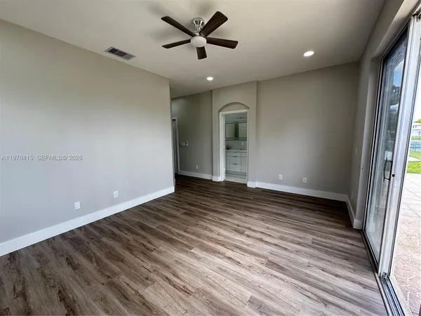 a view of empty room with wooden floor and fan