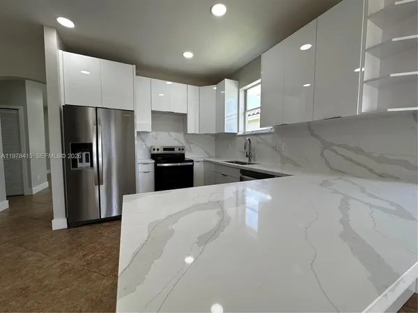 a large kitchen with stainless steel appliances kitchen island granite countertop a refrigerator a sink a stove and a sink