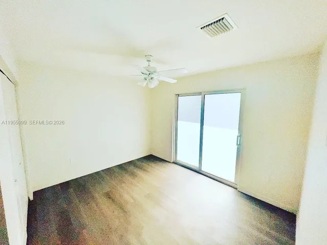 an empty room with a ceiling fan and wooden floor