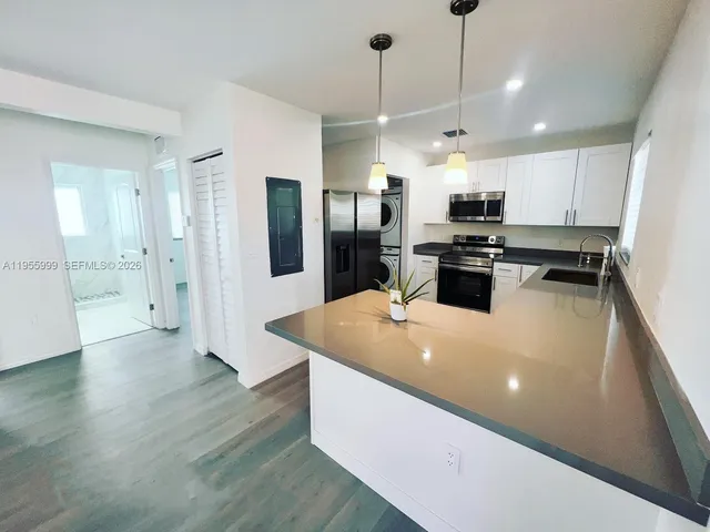 a large kitchen with stainless steel appliances granite countertop a sink a stove and a refrigerator