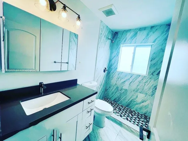 a bathroom with a sink a toilet and shower