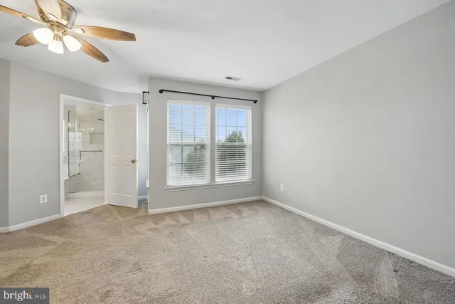 a view of an empty room with window and chandelier fan