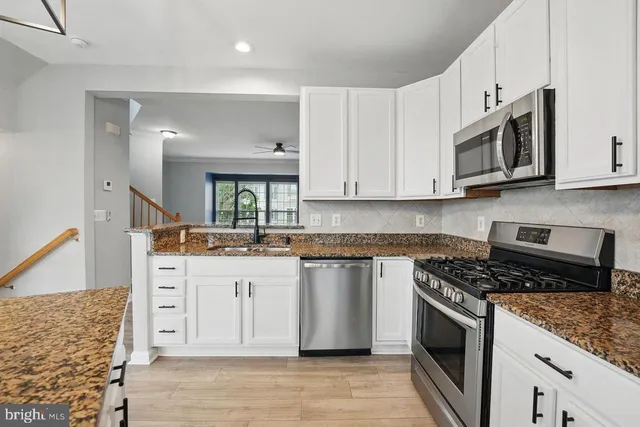 a kitchen with stainless steel appliances granite countertop a stove a sink and a microwave