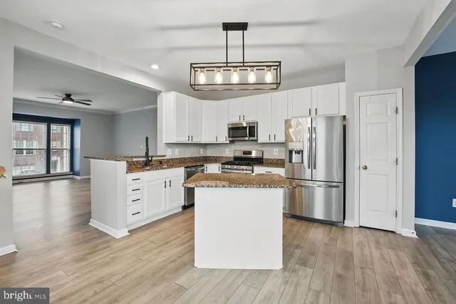 a kitchen with kitchen island white cabinets a refrigerator a oven a stove and a wooden floors