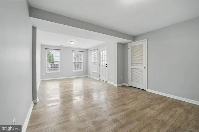 a view of an empty room with window and wooden floor