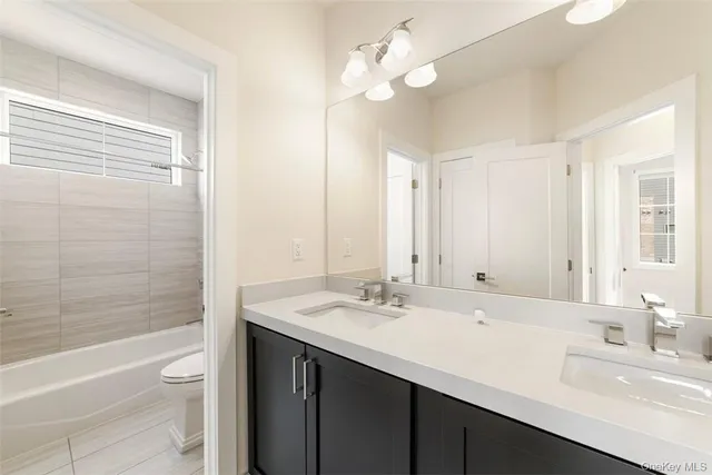 a bathroom with a double vanity sink a toilet and a bathtub