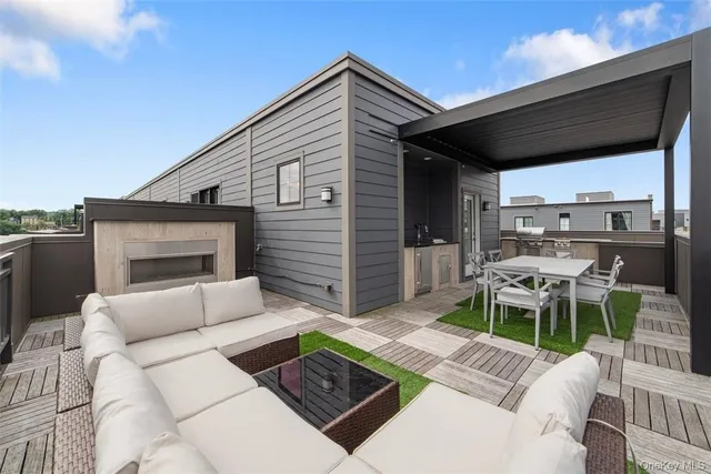 a view of a patio with couches table and chairs with wooden floor and fence