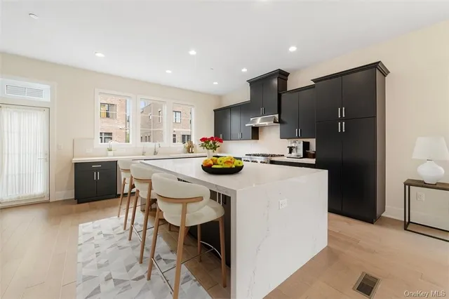 a kitchen with stainless steel appliances a sink a stove a refrigerator cabinets and a dining table