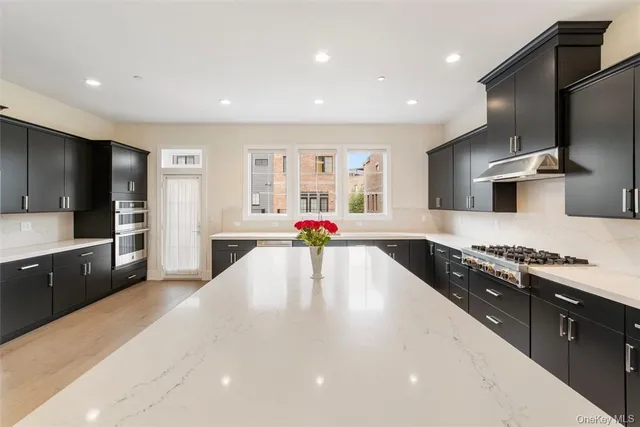 a large kitchen with stainless steel appliances a large counter top a stove a chimney a sink and a refrigerator