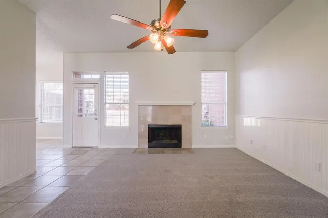 an empty room with windows and fireplace