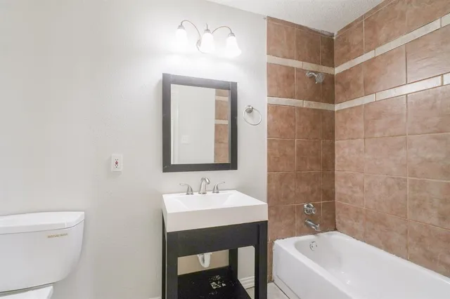 a bathroom with a bathtub shower sink mirror and toilet