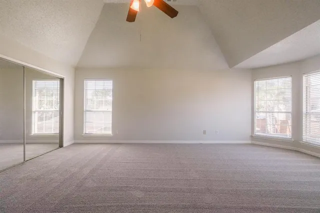 an empty room with chandelier fan and windows