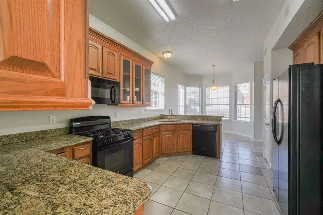 a kitchen with stainless steel appliances granite countertop a stove top oven a sink a counter space and cabinets