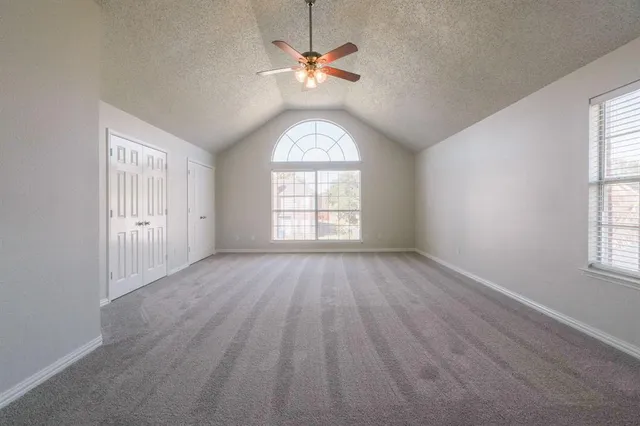 an empty room with wooden floor chandelier fan and windows