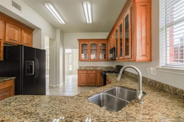 a kitchen with stainless steel appliances granite countertop a sink and a refrigerator