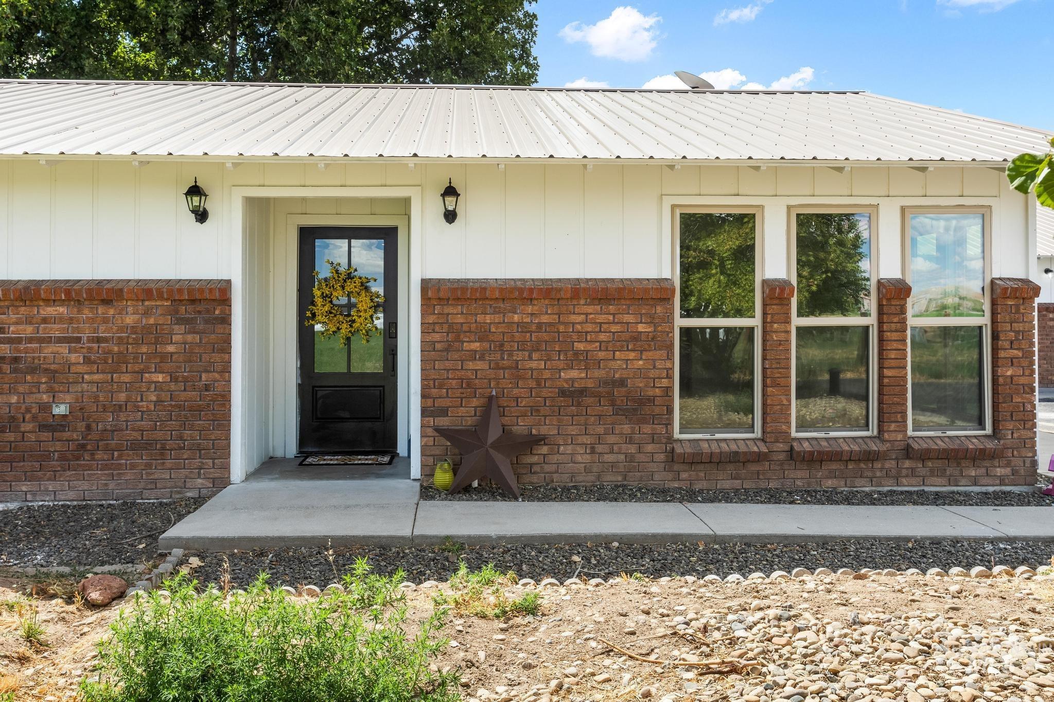 8500 Washoe Road Payette, ID 83661 - Photo 9 of 50 Doorway to property featuring a metal roof, brick siding, and board and batten siding