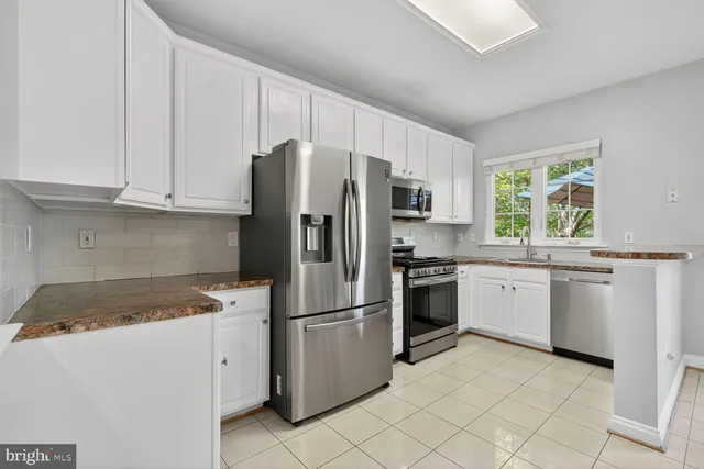 a kitchen with granite countertop white cabinets and stainless steel appliances