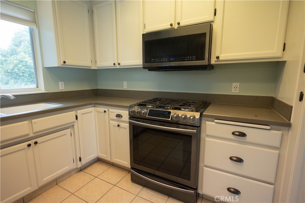 6042 Grange Road Corning, CA 96021 - Photo 13 of 38 a kitchen with stainless steel appliances granite countertop white cabinets and a stove top oven