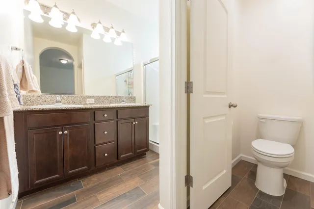 a bathroom with a granite countertop sink a toilet and a mirror