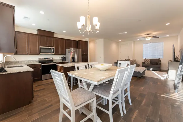 a kitchen with a dining table chairs and wooden floor