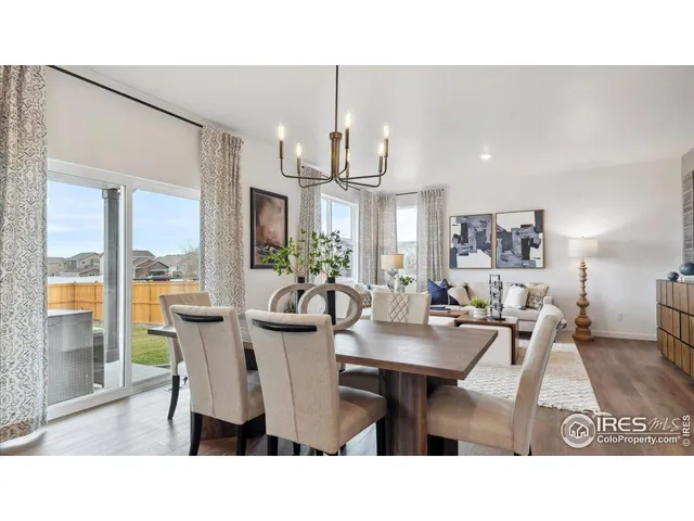 a dining room with kitchen island a dining table wooden floor and a chandelier