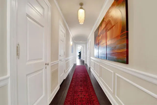 a view of a hallway with wooden floor and a bathroom