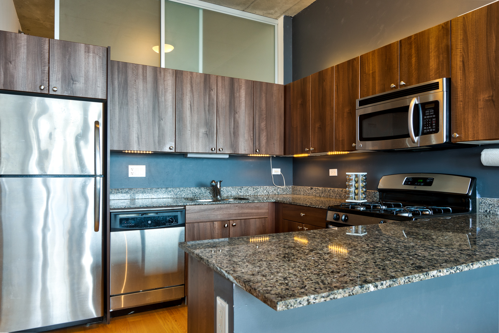 235 West Van Buren Street, Unit 3011 Chicago, IL 60607 - Photo 12 of 30 a kitchen with stainless steel appliances granite countertop a refrigerator a stove a sink cabinets and a counter space