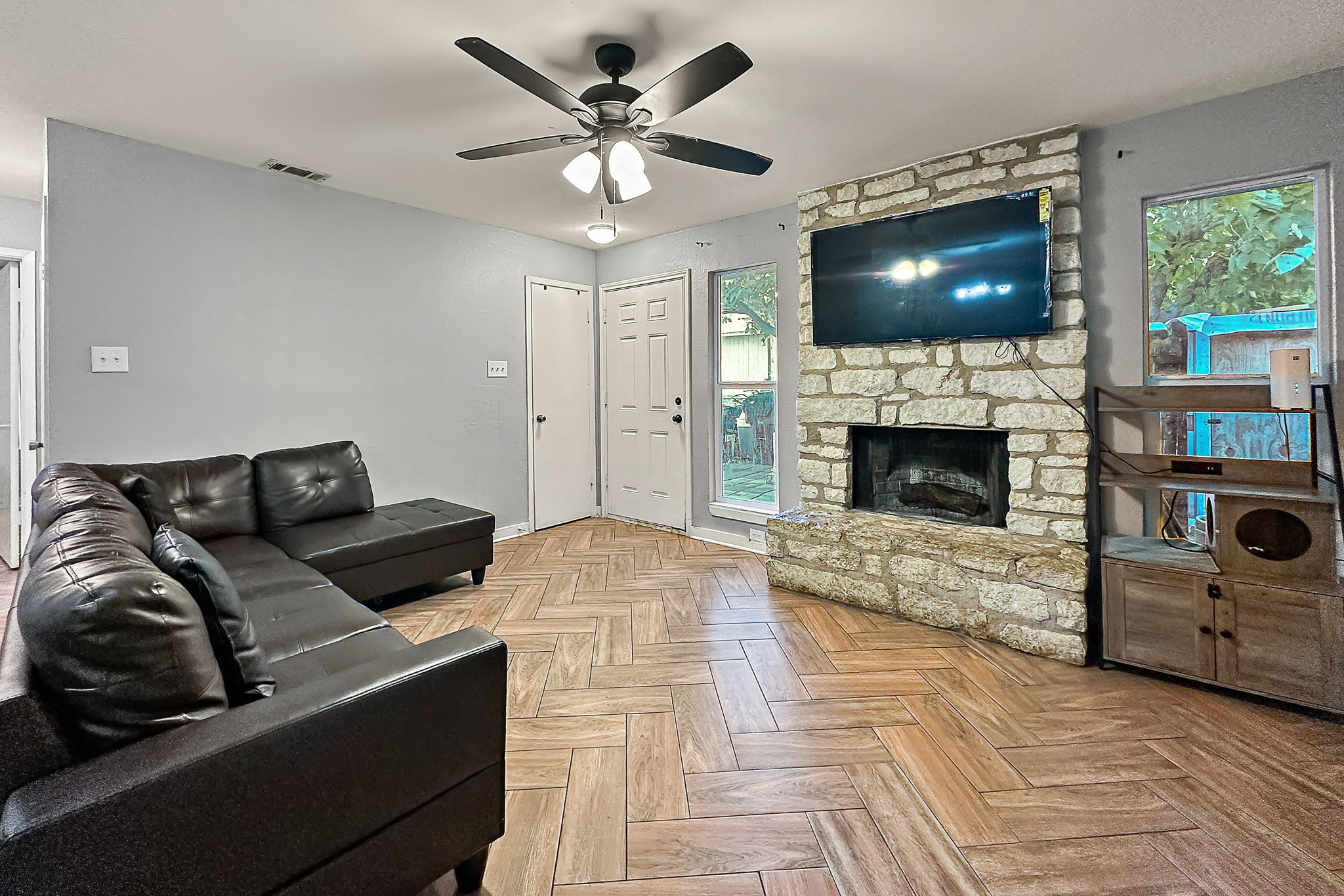 700 Misty Morning Way Round Rock, TX 78664 - Photo 22 of 36 Unit A - A cozy living space features a stone fireplace, herringbone wood-look tile flooring, and ample natural light.