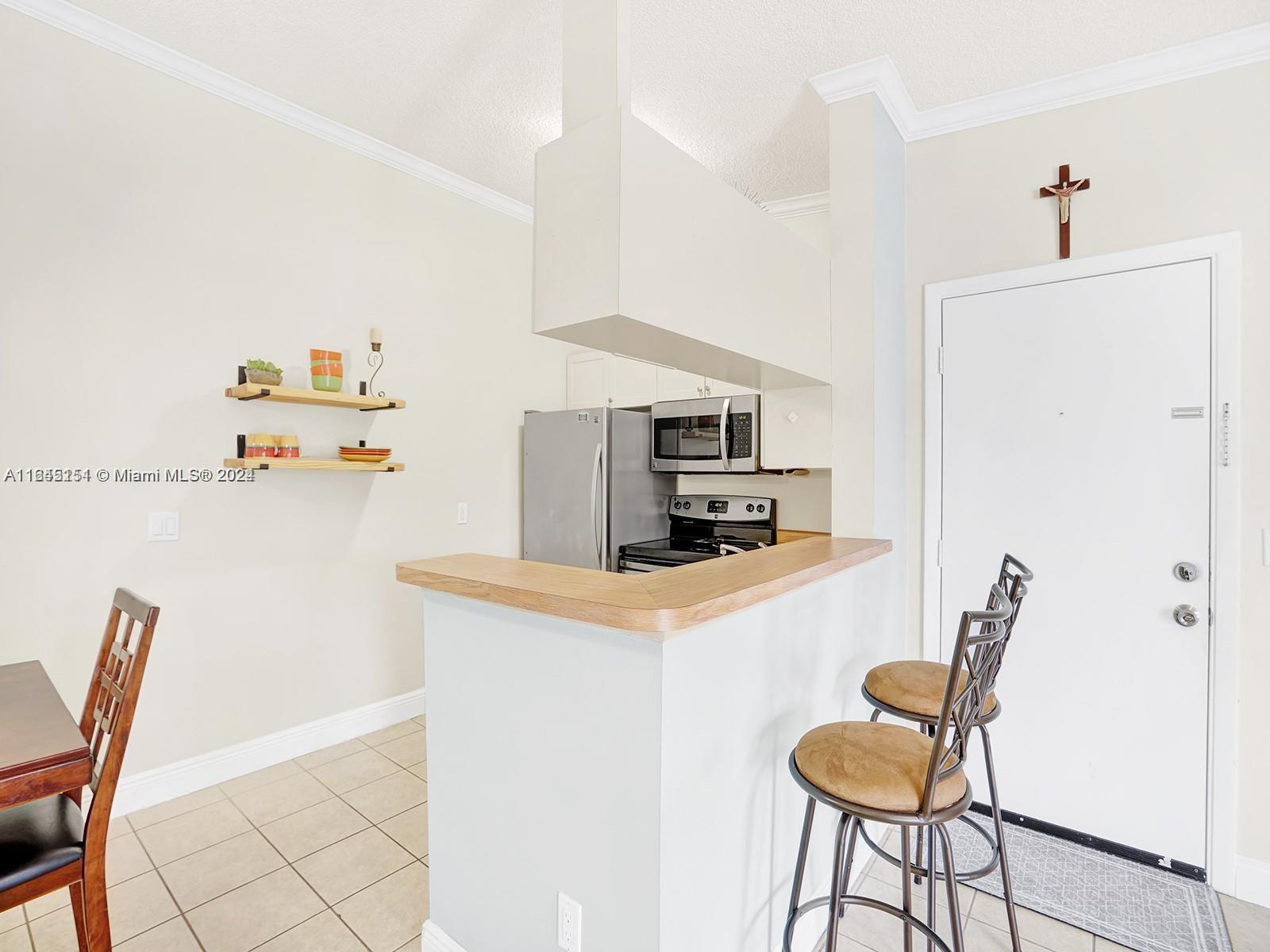 9727 Hammocks Boulevard, Unit 201D Miami, FL 33196 - Photo 11 of 25 a kitchen with stainless steel appliances a microwave a stove and white cabinets