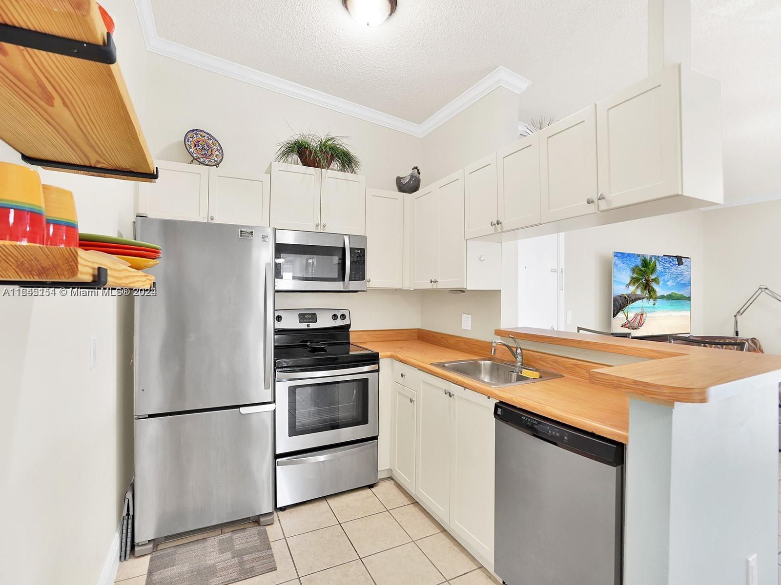 9727 Hammocks Boulevard, Unit 201D Miami, FL 33196 - Photo 12 of 25 a kitchen with stainless steel appliances granite countertop a stove a refrigerator and a sink