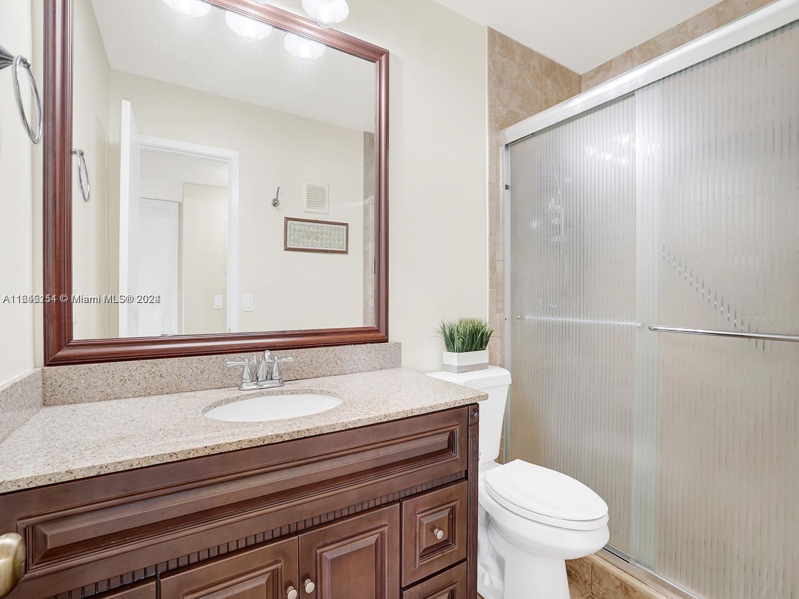 9727 Hammocks Boulevard, Unit 201D Miami, FL 33196 - Photo 4 of 25 a bathroom with a sink a toilet a mirror and shower