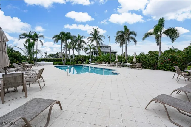 a view of a swimming pool with a lounge chair and palm trees