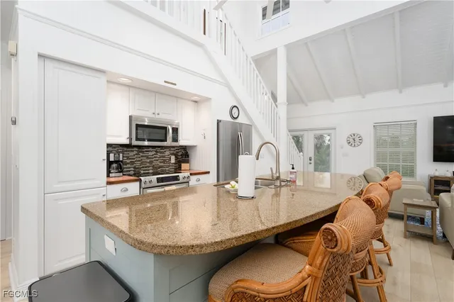 a kitchen with granite countertop a table chairs stove and microwave