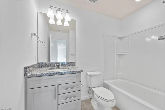 a bathroom with a granite countertop sink a toilet mirror and bathtub