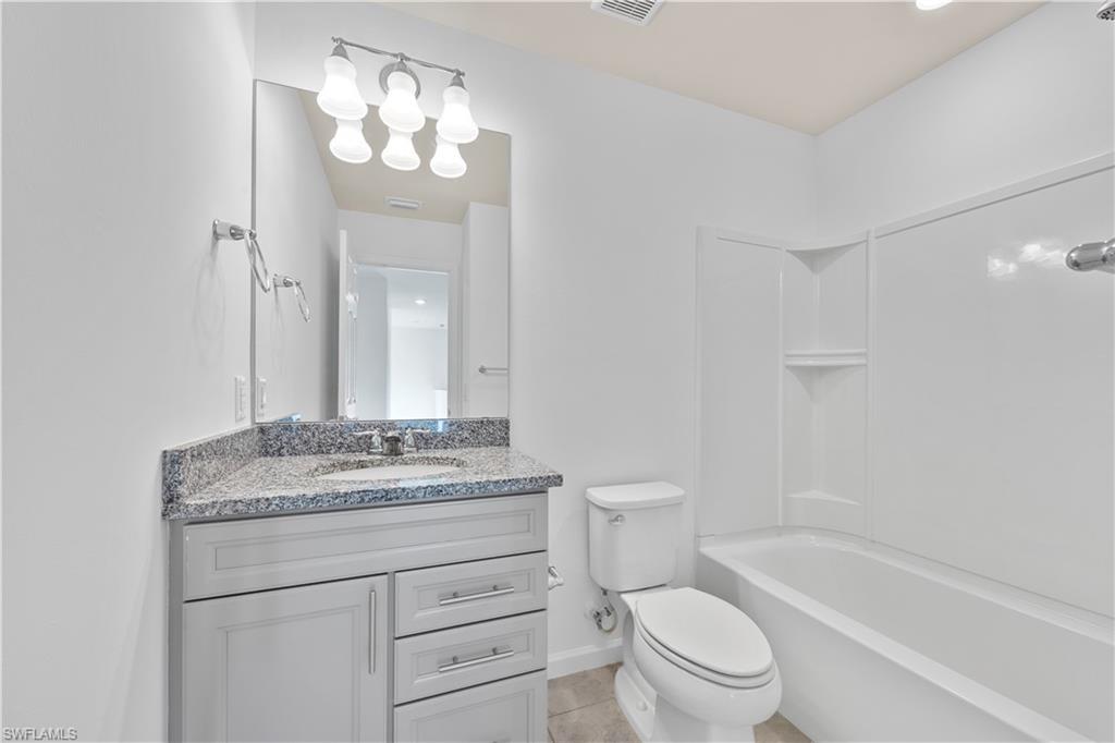 4583 Lamaida Lane Immokalee, FL 34142 - Photo 24 of 29 a bathroom with a granite countertop sink a toilet mirror and bathtub