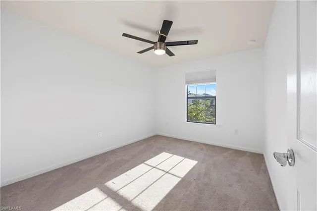 an empty room with ceiling fan and window